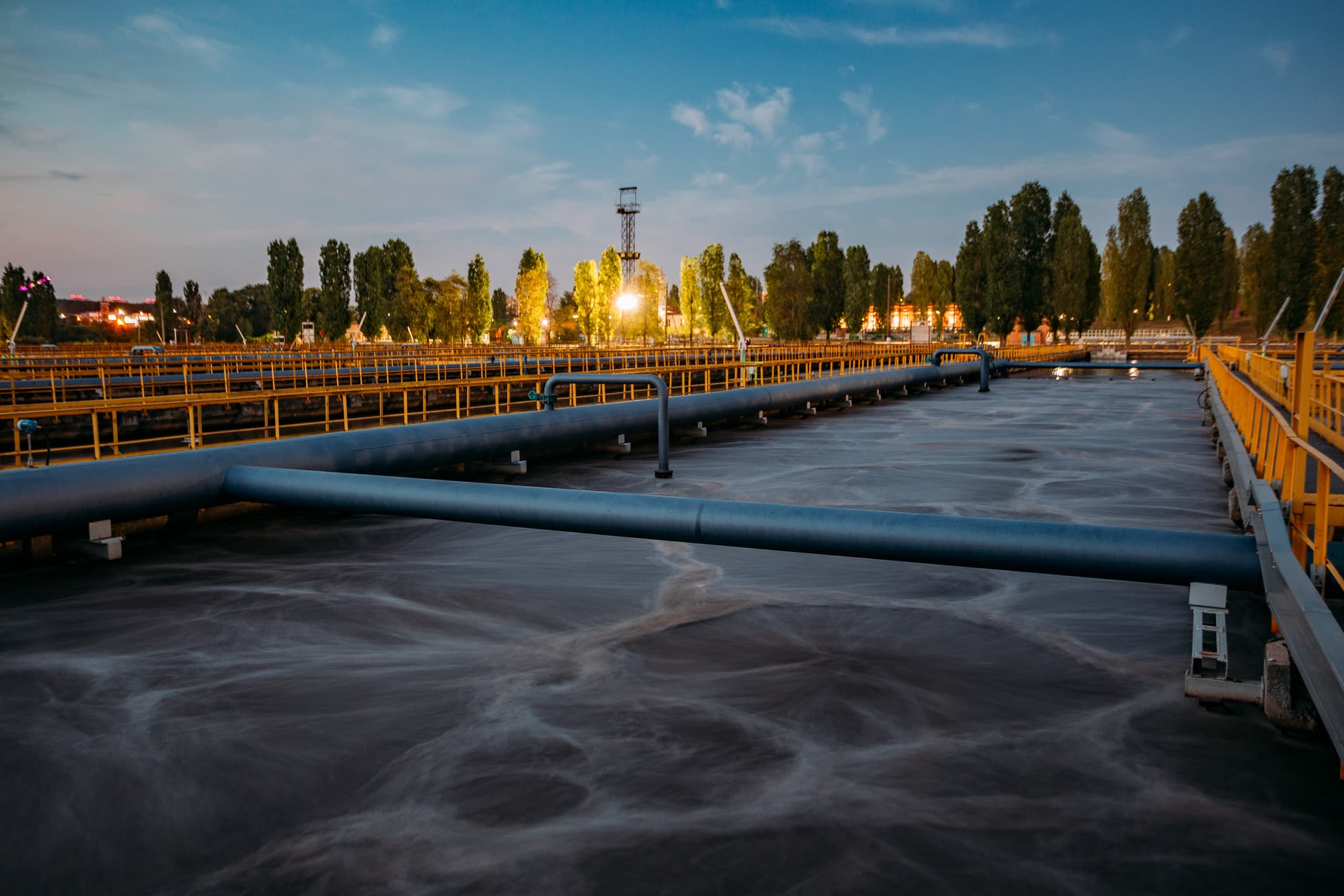 Tanks for aeration and biological purification of sewage at a water treatment facility at sunset.