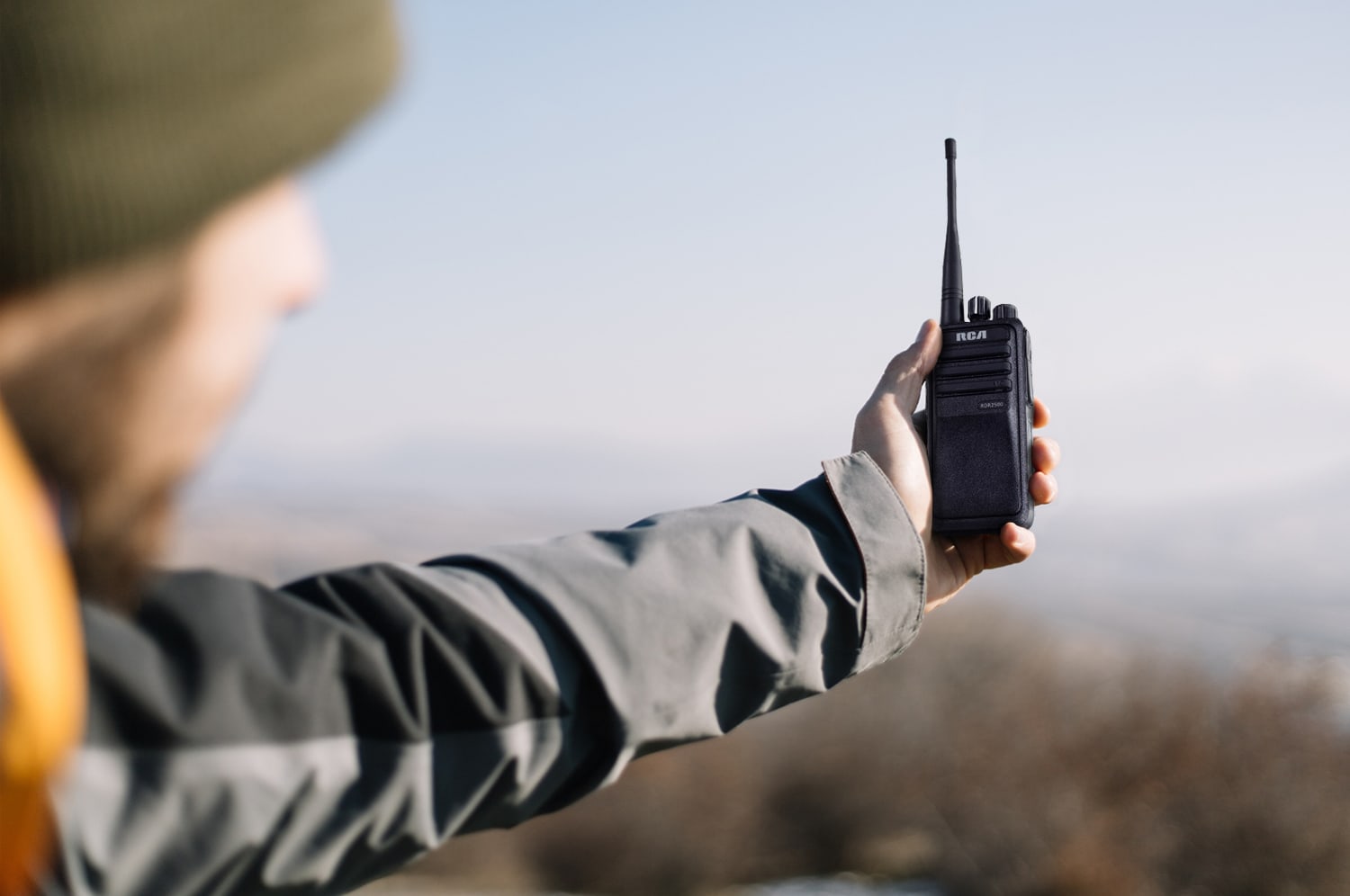 A field technician holds an RCA radio away from him to test coverage while outdoors.